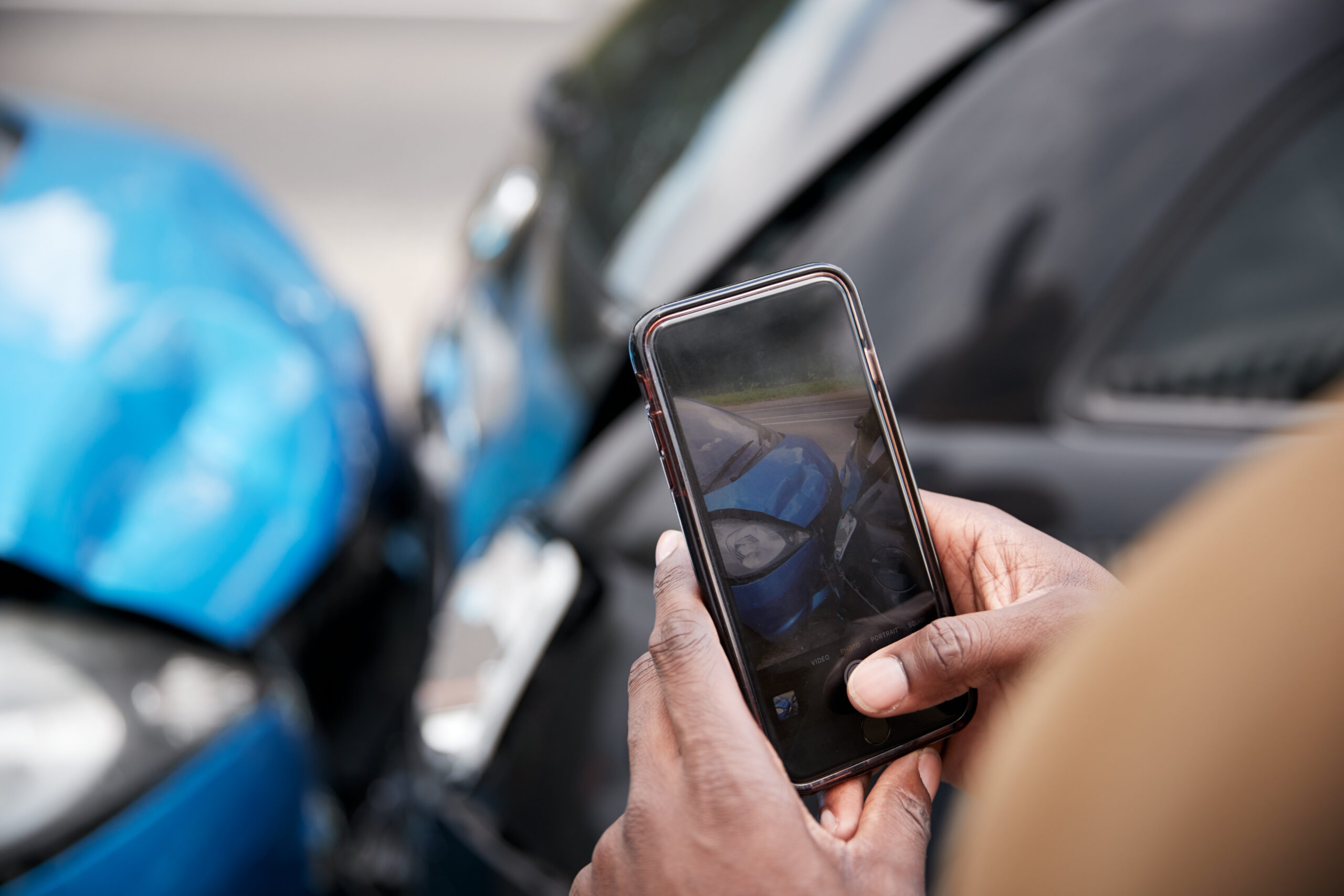 Male Motorist Involved In Car Accident Taking Picture Of Damage For Insurance Claim A smartphone lying face-up on a surface with push pins connected by red and blue strings, representing a network of social media connections. Wooden letter tiles spell out the names of apps such as Facebook, Instagram, Snapchat, and iMessage.