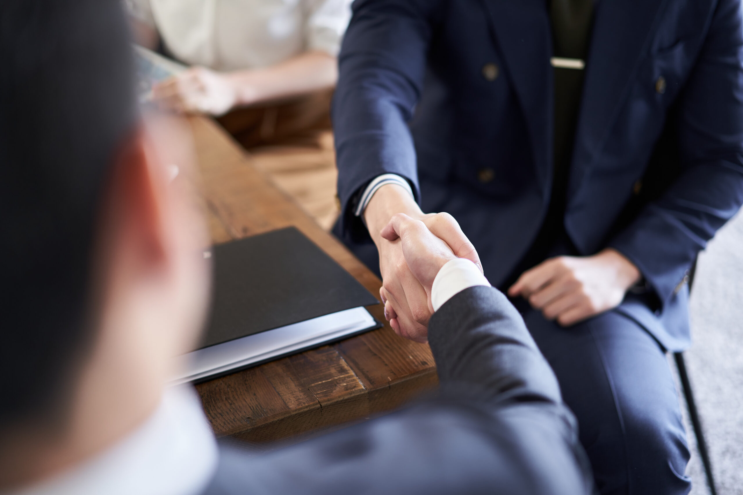 two people in suits sitting down shaking hands