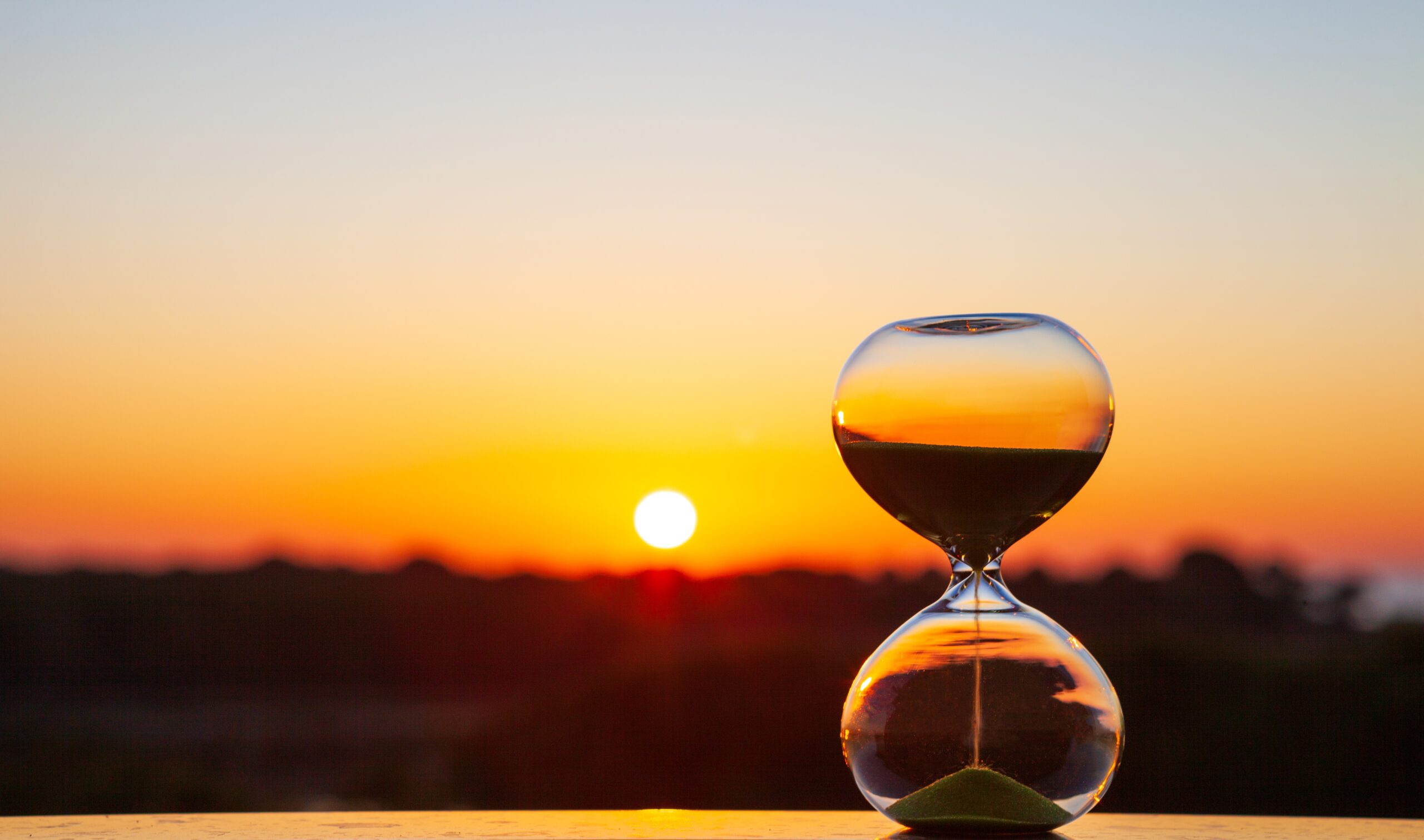 Hourglass at sunset or dawn on a blurry background, as a reminder of the passing time old truck with window smashed in