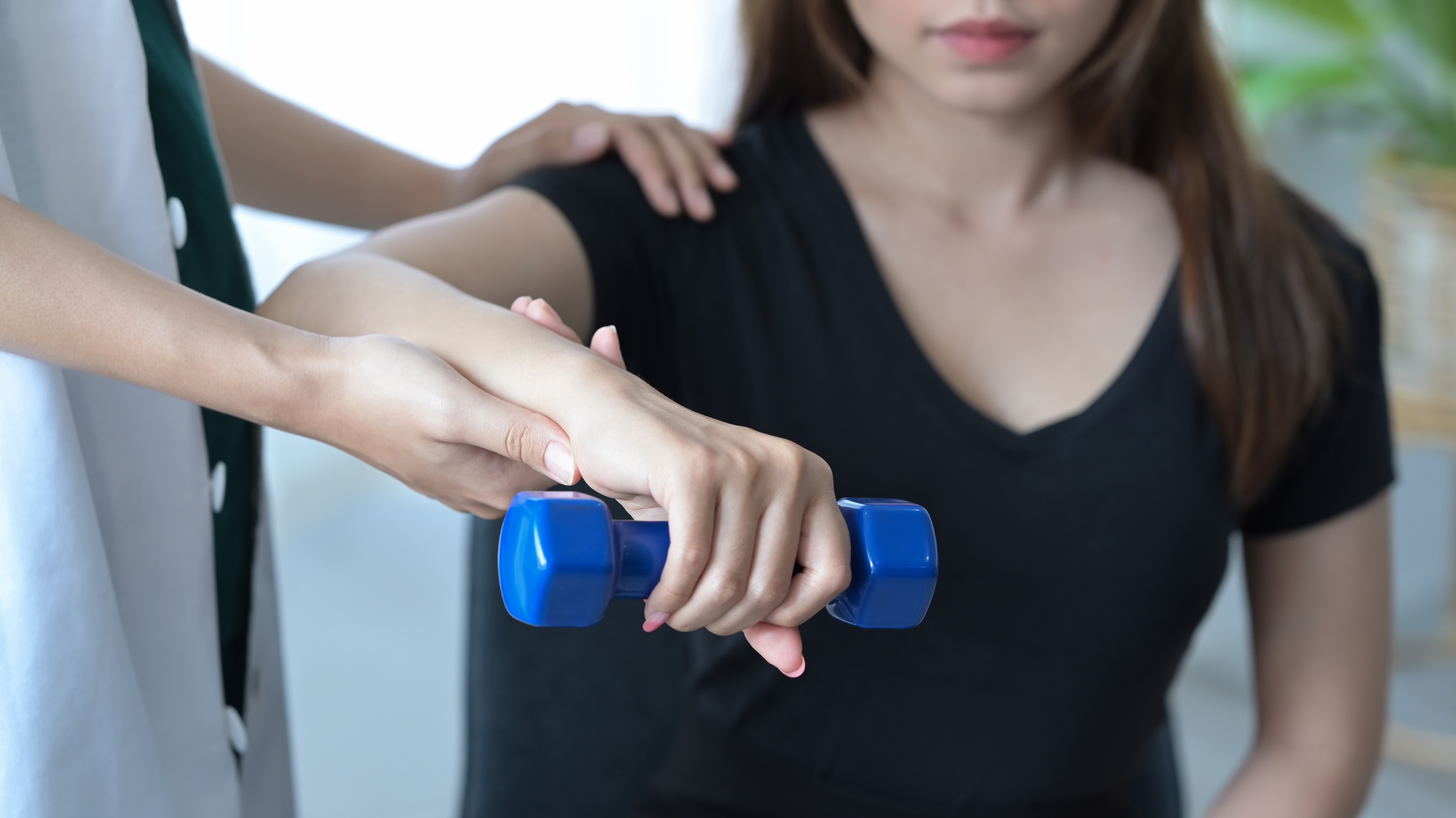 Physiotherapist giving exercise with dumbbell treatment about ar asphalt with cracks all through it